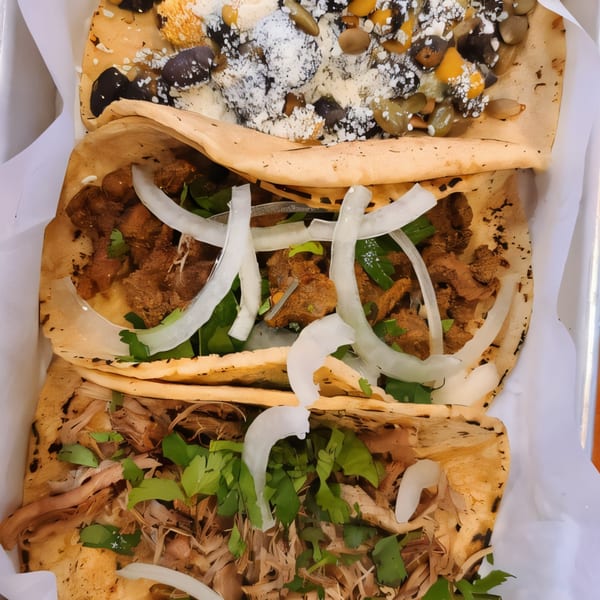Three Str8 up Tacos with various fillings, including meat, onions, cilantro, and seeds.