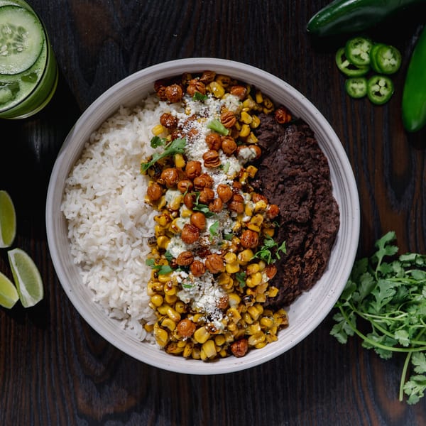 Overhead view of a Str8 up Tacos bowl with rice, black beans, corn, chickpeas, and cheese.